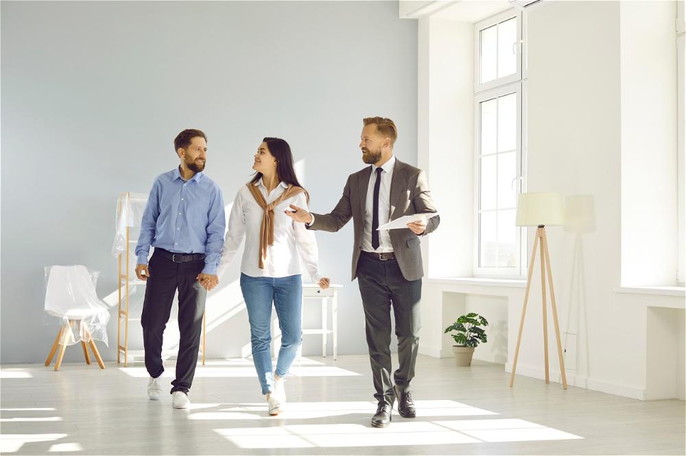 Couple touring home, real estate agent guiding.
